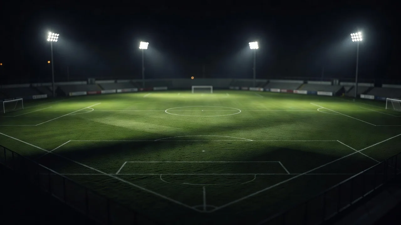 Campo de futebol iluminado por refletores visto do alto à noite